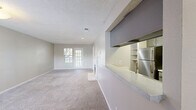 This well-appointed 2-bedroom, 2-bathroom single-story residence offers a thoughtfully designed layout ideal for comfortable everyday living. The open-concept living room is a standout feature, anchored by a classic white-mantled fireplace and bathed in natural light from a set of glass patio doors that invite the outdoors in. Plush wall-to-wall carpeting runs throughout the main living area, adding warmth and comfort underfoot. The kitchen connects seamlessly to the living space via a convenient pass-through counter with an overhead cabinet, and is equipped with stainless steel appliances, built-in shelving, and ample cabinetry. The generously sized primary bedroom features a ceiling fan, a window with natural light, and access to a dedicated walk-in closet. The second bedroom is equally comfortable, also carpeted and naturally lit through a window fitted with blinds. Both bathrooms are finished with light wood-look tile flooring, gray modern cabinetry, and tub-shower combinations. Additional closet storage is available throughout the unit. Textured ceilings are present throughout, complementing the neutral, warm color palette that ties the entire space together cohesively.