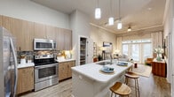 Located at 510 N Wilmington St in Raleigh, NC, this one-bedroom, one-bathroom residence offers a thoughtfully designed open-concept layout with high ceilings that create an airy, spacious feel throughout. The combined living, dining, and kitchen area serves as the heart of the home, highlighted by wood-look plank flooring, crown molding, and a ceiling fan with ample track lighting. The kitchen is equipped with stainless steel appliances, light wood cabinetry, a mosaic tile backsplash, quartz countertops, and a large center island with an undermount sink — ideal for both cooking and casual dining. A dedicated walk-in pantry provides exceptional storage. The living area opens to natural light through large glass doors, offering outdoor views and a welcoming ambiance. The bedroom features a bold accent wall, natural light from windows with patterned drapes, and a generous walk-in closet with wire shelving. The bathroom is finished with large-format tile, a soaking tub with shower, and a vanity with wood cabinetry and a quartz countertop beneath an arched architectural detail. Additional spaces include a laundry area and a utility room, rounding out a highly functional and stylish home.