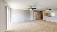 Located at 4828 Zenith St in Metairie, Louisiana, this two-story residence offers two bedrooms and three bathrooms spread evenly across both floors. The main level opens into a generous combined living and dining area finished with plush wall-to-wall carpeting and a ceiling fan overhead. A pass-through window connects the living area to the kitchen, which features rich cherry wood cabinetry, dark granite-style countertops, wood-look vinyl flooring, black appliances including an electric range and refrigerator, and a window that brings in natural light. A carpeted staircase with a classic white banister leads to the upper floor. The primary bedroom is a well-proportioned retreat with a ceiling fan, carpeted floors, and direct access to a dedicated bathroom area featuring dark granite countertops and warm cherry wood vanities. A secondary bedroom on the upper level mirrors the same comfortable finishes, including carpeting and a ceiling fan, with a window framing outside views. Three bathrooms are distributed throughout the home to serve both floors conveniently. Each bathroom is outfitted with dark countertops and warm wood cabinetry. A dedicated closet and multiple staircases round out the functional layout of this well-organized Metairie residence.