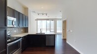 This one-bedroom, one-bathroom unit offers a well-designed open-concept layout with a comfortable interior footprint complemented by an exceptionally large private outdoor terrace—nearly half the size of the interior living space—providing rare outdoor living opportunities in an urban setting.

The kitchen is a standout feature, equipped with dark espresso cabinetry extending to the ceiling, stainless steel appliances including a refrigerator, range, and built-in microwave, a mosaic tile backsplash, light quartz countertops, and a peninsula with an undermount sink that opens seamlessly to the living area. Rich, dark hardwood flooring flows consistently throughout the interior, adding warmth and continuity.

The living area is open and flexible, benefiting from floor-to-ceiling windows and a sliding glass door that connects directly to the expansive terrace. The terrace features tiled flooring, a brick parapet wall with a sleek metal railing, and panoramic views of a dense downtown skyline.

The bedroom includes a ceiling fan and access to a walk-in closet outfitted with wire shelving. The bathroom features a soaking tub with full-surround large-format beige tile and recessed lighting, delivering a clean, modern finish throughout.