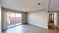 Located at 2130 N Marks Ave in Fresno, CA, this single-story, 3-bedroom, 2-bathroom home offers a well-organized layout across one floor. Light-toned wood-look flooring runs throughout, complemented by neutral gray walls and textured ceilings that lend a clean, cohesive aesthetic to every room.

The open living and dining area is spacious and airy, featuring a ceiling fan and seamless flow into the adjacent spaces. Exposed ceiling beams add a subtle architectural detail to the living area. A sliding glass door connects the living space directly to a private patio, enclosed by a wood fence for added privacy.

The combined kitchen and dining area is a standout feature, showcasing white shaker-style cabinetry, dark granite countertops, a stone tile backsplash, stainless steel appliances including a refrigerator and range, and a double sink. Track lighting overhead keeps the galley-style kitchen well-lit and functional.

Each of the three bedrooms includes wood-look flooring, neutral walls, and natural light from windows with blinds. The primary bedroom offers direct access to its own bathroom, which includes a glass-enclosed shower. A second full bathroom serves the remaining bedrooms. Additional features include six closets, a dedicated laundry area, a utility room, and a hallway connecting the private quarters of the home.
