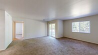 Located at 1846 Hamilton Rd in Okemos, MI, this single-floor residence offers four bedrooms and two full bathrooms across a compact, efficiently arranged floor plan. The layout, as seen in the dollhouse view, organizes living spaces in a practical configuration with clear separation between the kitchen, living area, and bedrooms.

The kitchen is equipped with dark wood-grain cabinetry, white laminate countertops, a white electric range, and a dishwasher, all set on stone-patterned tile flooring. The functional L-shaped layout provides ample counter and storage space for everyday use.

The living area is generously proportioned, featuring soft wall-to-wall carpeting, neutral beige walls, and large sliding glass doors alongside a picture window that invite natural light and provide views of the surrounding greenery. The bedrooms continue the carpeted, neutral aesthetic, offering a clean and versatile canvas. The expansive primary bedroom includes a built-in closet with louvered bifold doors and a ceiling fan. Additional bedrooms feature windows with outdoor views and plentiful natural light.

Both bathrooms are identically appointed with white tiled tub-shower combinations, chrome fixtures, light countertops, and stone-patterned tile flooring, conveying a clean and consistent design throughout.