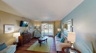 Located at 2530 Chelsea Ln in Fort Mitchell, Kentucky, this single-floor residence offers a thoughtfully designed layout filled with color and character. The living room serves as the heart of the home, showcasing rich hardwood flooring, a bold teal accent wall adorned with a large framed mirror, and sliding glass doors that flood the space with natural light and provide direct access to a lush outdoor patio. The adjoining dining area features hardwood floors, a pendant light fixture, and a bright window, creating an inviting space for gatherings. The kitchen is well-appointed with dark espresso cabinetry, stone-look countertops, a tile mosaic backsplash, and black appliances, offering both style and functionality in a well-organized galley layout. The bedroom is a warm retreat highlighted by a striking golden-yellow accent wall, plush carpeting, and a sliding closet with built-in shelving, complemented by natural light through a window. Two bathrooms are finished with neutral tones, dark-framed mirrors, and brushed nickel fixtures, providing clean and functional spaces. Throughout the home, a cohesive palette of teal, gold, and warm neutrals ties each room together, creating a lively yet comfortable ambiance.