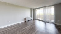Located at 2000 Riverside Dr in Richmond, Virginia, this single-floor residence offers a thoughtfully updated interior with modern finishes throughout. The kitchen is a standout feature, showcasing crisp white shaker cabinetry, granite countertops with subtle speckled detailing, a gray subway tile backsplash, and stainless steel appliances including a Frigidaire dishwasher and refrigerator. Wood-look flooring runs through the kitchen, adding warmth to the clean, contemporary aesthetic. The living area is generously proportioned, featuring the same durable wood-look flooring and soft neutral wall tones that lend a calm, airy atmosphere. Large sliding glass doors open directly to a private balcony, inviting natural light deep into the space and providing pleasant outdoor views of the surrounding greenery. The bedroom is a comfortable, open space with coordinating flooring and light-toned walls, connected to the rest of the unit via a hallway. The bathroom is cleanly designed with white cabinetry, a sliding glass enclosed tub-shower combination, and wood-look flooring that ties the space together. Throughout the residence, consistent finishes and neutral tones create a cohesive, move-in ready environment that balances functionality with modern style.