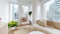 Located in the heart of Toronto's Financial District, this thoughtfully designed one-bedroom, one-bathroom unit offers a refined urban living experience. The layout flows from a crisp, well-lit hallway — finished with elegant herringbone hardwood flooring and clean white walls — into an open-concept living and kitchen area.

The living room is a standout feature, boasting multiple floor-to-ceiling windows that frame sweeping panoramic views of the Toronto skyline, including a striking sightline toward the CN Tower. Natural light floods the space throughout the day, creating a bright and airy atmosphere that complements the neutral, minimalist interior palette.

The bedroom is a calm retreat, featuring a large window with city views and warm herringbone hardwood floors. Its cozy yet functional scale makes efficient use of every square foot.

The bathroom is finished with sage-green vertical wall tiles surrounding a soaker tub and shower combination, contrasted by crisp white floor tiles and matte black fixtures — a clean, contemporary aesthetic throughout.

A compact, modern kitchen with white cabinetry integrates seamlessly into the open-plan living and dining area. Two hallways provide practical connectivity throughout the unit. Overall, the space delivers a polished, light-filled environment ideal for those seeking a sophisticated residence in downtown Toronto.