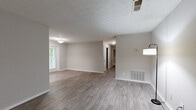 This single-story, 3-bedroom, 2-bathroom home offers a thoughtfully designed layout with modern finishes throughout. The open living area is anchored by light gray wood-look flooring, neutral-toned walls, and a textured ceiling, creating a clean and inviting atmosphere. Natural light filters in through a window overlooking lush greenery, enhancing the airy feel of the space. A hallway connects the living area to the bedrooms, providing a practical flow throughout the home.

The kitchen features a galley-style layout with white cabinetry, granite countertops, a subway tile backsplash, and stainless steel appliances, including a gas range and built-in microwave. The primary bedroom is generously sized, carpeted for comfort, and includes a walk-in closet equipped with wire shelving systems for ample storage. The two bathrooms are finished with white vanities, granite countertops, and framed mirrors.

Additional highlights include a louvered storage closet in the living area and a private outdoor deck with a white railing, offering tranquil views of a surrounding wooded area. The home combines functional design with comfortable, contemporary finishes throughout.