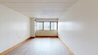 Located at 3812 Bates St in Pittsburgh's 15213 zip code, this two-bedroom, two-bathroom residence offers a practical and well-organized single-floor layout. The living room is the heart of the home, featuring light wood laminate flooring, neutral white walls, warm wood baseboards, and a large window fitted with vertical blinds that allow generous natural light to fill the space. An open sightline connects the living area to the galley-style kitchen, which is outfitted with warm honey-toned wood cabinetry, white countertops, tile flooring, a stainless steel refrigerator, a stainless range, and a dishwasher — providing ample storage and functionality. Both bedrooms continue the light wood flooring theme and feature windows that bring in natural light, with the primary bedroom offering a comfortable and spacious feel. Four closets throughout the unit provide substantial storage. The two bathrooms are finished with white tile surrounds, soaking tubs with shower fixtures, and wood-accented vanities. The entrance provides a welcoming transition into the home. Overall, the unit presents a clean, neutral palette with consistent finishes throughout, making it a functional and comfortable residence.