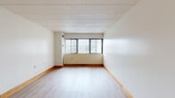 Located at 3812 Bates St in Pittsburgh's 15213 zip code, this two-bedroom, two-bathroom residence offers a practical and well-organized single-floor layout. The living room is the heart of the home, featuring light wood laminate flooring, neutral white walls, warm wood baseboards, and a large window fitted with vertical blinds that allow generous natural light to fill the space. An open sightline connects the living area to the galley-style kitchen, which is outfitted with warm honey-toned wood cabinetry, white countertops, tile flooring, a stainless steel refrigerator, a stainless range, and a dishwasher — providing ample storage and functionality. Both bedrooms continue the light wood flooring theme and feature windows that bring in natural light, with the primary bedroom offering a comfortable and spacious feel. Four closets throughout the unit provide substantial storage. The two bathrooms are finished with white tile surrounds, soaking tubs with shower fixtures, and wood-accented vanities. The entrance provides a welcoming transition into the home. Overall, the unit presents a clean, neutral palette with consistent finishes throughout, making it a functional and comfortable residence.