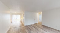 Located at 19605 SW Boones Ferry Rd in Tualatin, Oregon, this single-floor unit offers a clean, updated interior designed for comfortable everyday living. The open layout connects the living area to the rest of the unit seamlessly, with light wood-style flooring extending throughout the main living spaces, contributing to a bright and cohesive aesthetic.

The living area is generously proportioned, featuring white walls, a textured ceiling, and large vertical-blind-covered sliding glass doors that allow abundant natural light to filter in while providing access to an outdoor area. The open sightlines create a spacious feel, with clear pathways leading to additional rooms.

The kitchen is efficiently designed and features grey shaker-style cabinetry, white countertops, a stainless steel sink, and a full suite of stainless steel appliances including a refrigerator and dishwasher. A window above the counter brings in additional natural light.

A separate bedroom offers wood-style flooring, a large window, and a closet with direct door access. The bathroom includes a vanity with a sink, mirror, and brushed nickel fixtures set against clean white walls. Overall, the unit presents a fresh, well-maintained interior throughout.