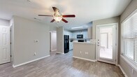 This single-story, 1-bedroom, 1-bathroom unit offers a thoughtfully designed layout that maximizes its compact footprint. The open-concept living and kitchen area serves as the heart of the space, featuring wood-look flooring, neutral gray walls, and a ceiling fan with light fixture. Large windows fitted with blinds allow natural light to fill the room, creating a bright and welcoming atmosphere.

The kitchen is a standout feature, equipped with white shaker-style cabinetry, crisp white countertops, and a classic subway tile backsplash. A stainless steel double-basin sink sits beneath a window, and the space is fully outfitted with black appliances, including a refrigerator, range, microwave, and dishwasher. A peninsula counter provides additional workspace and helps define the transition between the kitchen and living areas.

The bedroom offers a comfortable and private retreat, complete with plush carpeting, a ceiling fan, a window for natural light, and a dedicated closet. A hallway connects the main living spaces to the bedroom and bathroom. The bathroom features wood-look flooring, a white vanity with ample cabinetry, and a full tub-shower combination with clean white tile surround.