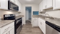 This updated 1-bedroom, 1-bathroom unit has been thoughtfully refreshed throughout its single floor. The galley-style kitchen stands out as a highlight of the renovation, featuring crisp white shaker cabinetry with modern hardware, granite-look countertops, wood-look plank flooring, and a full suite of stainless steel appliances including a refrigerator, electric range, microwave, and dishwasher. A pass-through window connects the kitchen to the rest of the unit, enhancing the open feel.

The living area is generously proportioned, finished with neutral carpet and baseboard heating along the perimeter. A large sliding glass door dressed with vertical blinds floods the space with natural light and provides access to outdoor views, creating an airy, comfortable atmosphere.

The bedroom offers ample room with soft carpet, baseboard heating, and a full-width bifold closet providing substantial storage. The layout also includes an additional closet space accessible from the hallway.

The bathroom is clean and functional, featuring a full tub-shower combination in white, wood-look flooring, and neutral wall tones. Overall, the unit presents a cohesive, move-in-ready aesthetic with modern updates balanced against a comfortable, practical layout.