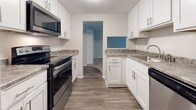 This updated 1-bedroom, 1-bathroom unit has been thoughtfully refreshed throughout its single floor. The galley-style kitchen stands out as a highlight of the renovation, featuring crisp white shaker cabinetry with modern hardware, granite-look countertops, wood-look plank flooring, and a full suite of stainless steel appliances including a refrigerator, electric range, microwave, and dishwasher. A pass-through window connects the kitchen to the rest of the unit, enhancing the open feel.

The living area is generously proportioned, finished with neutral carpet and baseboard heating along the perimeter. A large sliding glass door dressed with vertical blinds floods the space with natural light and provides access to outdoor views, creating an airy, comfortable atmosphere.

The bedroom offers ample room with soft carpet, baseboard heating, and a full-width bifold closet providing substantial storage. The layout also includes an additional closet space accessible from the hallway.

The bathroom is clean and functional, featuring a full tub-shower combination in white, wood-look flooring, and neutral wall tones. Overall, the unit presents a cohesive, move-in-ready aesthetic with modern updates balanced against a comfortable, practical layout.