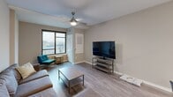 Located at 405 S Main St in downtown Ann Arbor, Michigan, this modern single-floor unit offers four bedrooms and four bathrooms within a thoughtfully designed layout. The open-concept living and dining area flows seamlessly into the kitchen, which features two-tone cabinetry with white upper and dark lower cabinets, stone-look quartz countertops, stainless steel appliances including a refrigerator, electric range, and microwave, and a large peninsula with bar seating and pendant lighting — ideal for both casual dining and entertaining. Hardwood-style flooring runs throughout the common areas and bedrooms, complementing the neutral, warm-toned walls. Each bedroom is well-proportioned, includes a ceiling fan, and is paired with its own private bathroom featuring a tub-shower combo with white subway tile, a dark-cabinet vanity, and stone-look countertops. The primary bedroom offers ample space with an attached closet. Additional spaces include a pantry, dedicated laundry room, utility rooms, and a hallway connecting all areas. Select bedrooms offer large windows with views of the surrounding Ann Arbor streetscape. The overall ambiance is clean, contemporary, and functional, suited for modern urban living.