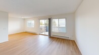 Located in Seattle's desirable Magnolia neighborhood, this one-bedroom, one-bathroom residence offers a well-designed layout with thoughtful finishes throughout. Light-toned luxury vinyl plank flooring runs through the main living areas, complementing the bright, neutral palette of white walls and clean-lined trim.

The combined living and dining room is a standout space, filled with natural light from large windows and a sliding glass door that opens to a private balcony — offering open views of the surrounding Seattle landscape. The galley-style kitchen is outfitted with white shaker cabinetry accented by matte black hardware, light stone countertops, stainless steel appliances, recessed lighting, and a black-fixture sink.

The bathroom features a modern vanity with a white countertop, undermount sink, matte black faucet, and a large wall mirror with overhead lighting. The bedroom is finished with plush carpet, a window with garden views, and generous closet space — with a total of four closets throughout the unit providing excellent storage. A dedicated in-unit laundry closet houses a stacked washer and dryer. The hallway connects all areas efficiently, completing this practical and polished Seattle residence.