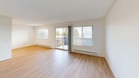 Located in Seattle's desirable Magnolia neighborhood, this one-bedroom, one-bathroom residence offers a well-designed layout with thoughtful finishes throughout. Light-toned luxury vinyl plank flooring runs through the main living areas, complementing the bright, neutral palette of white walls and clean-lined trim.

The combined living and dining room is a standout space, filled with natural light from large windows and a sliding glass door that opens to a private balcony — offering open views of the surrounding Seattle landscape. The galley-style kitchen is outfitted with white shaker cabinetry accented by matte black hardware, light stone countertops, stainless steel appliances, recessed lighting, and a black-fixture sink.

The bathroom features a modern vanity with a white countertop, undermount sink, matte black faucet, and a large wall mirror with overhead lighting. The bedroom is finished with plush carpet, a window with garden views, and generous closet space — with a total of four closets throughout the unit providing excellent storage. A dedicated in-unit laundry closet houses a stacked washer and dryer. The hallway connects all areas efficiently, completing this practical and polished Seattle residence.