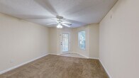 Located at 8465 Patriot Boulevard in North Charleston, SC, this single-floor, 2-bedroom, 2-bathroom residence offers a well-organized and functional layout. The living room is a comfortable, carpeted space featuring a ceiling fan with light fixture, a textured ceiling, neutral cream-toned walls, and natural light streaming in through a glass-paned exterior door and an adjacent window offering views of lush outdoor greenery.

The kitchen is efficiently designed in an L-shaped configuration, outfitted with white cabinetry, open shelving, light countertops, a double stainless steel sink, and a white electric range with overhead ventilation. Tile flooring adds a clean, practical finish to the space.

Both bedrooms are carpeted and include ceiling fans, neutral walls, and windows that bring in natural light. The primary bedroom features a private en-suite bathroom and a dedicated closet with built-in shelving. The second bedroom also includes its own closet with wire shelving for added storage.

Each bathroom includes a tub-shower combo, toilet, and tile flooring, with one featuring a single-sink vanity with cabinetry. A dedicated laundry area with washer hookup, wire overhead shelving, and tile flooring rounds out the practical amenities of this well-appointed residence.