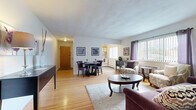 Located at 222 Milford St in Rochester, NY, this well-appointed one-bedroom, one-bathroom unit offers a thoughtfully designed single-floor layout. Warm hardwood flooring flows throughout the main living areas, lending a cohesive and inviting feel to the space.

The open-concept living and dining area is the heart of the unit, bathed in natural light from large windows dressed with vertical blinds and decorative curtains. The living area provides ample room for seating, while the adjacent dining space comfortably accommodates a round table and chairs. Framed artwork and clean white walls contribute to a bright, welcoming ambiance.

The kitchen is efficiently laid out with warm wood-trimmed cabinetry, white lower cabinets, light countertops, a stainless steel sink, and a dishwasher — offering practical functionality in a compact footprint. Light wood-style flooring continues through this space.

The bedroom is a comfortable retreat, featuring hardwood floors, a window with natural views, a closet with sliding wood-panel doors, and enough room for a full furniture arrangement.

The bathroom includes a full tub/shower combo with white tile surround and light tile flooring, providing a clean and functional finish. A hallway connects the rooms, completing this efficient and practical layout.