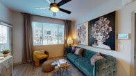 This single-floor residence combines modern finishes with bold, eclectic design to create a cohesive and inviting living environment. The open-concept layout connects the kitchen and living area seamlessly, anchored by light wood-style flooring that extends throughout the main living spaces.

The kitchen is well-appointed with wood-grain flat-front cabinetry, granite composite countertops, a spacious peninsula with bar seating, and a full suite of stainless steel appliances including a refrigerator with ice maker, electric range, and built-in microwave. Subway tile backsplash and pendant lighting add refined detail to the space.

The living area features a ceiling fan, a large window with horizontal blinds allowing ample natural light, and striking large-format portrait artwork that serves as a bold focal point. Two bedrooms are carpeted and each includes a ceiling fan, window with exterior views, and ample room for furnishings. The bathroom offers a granite-topped wood-tone vanity, a tub-shower combination, hardwood-style flooring, and recessed lighting. Warm neutral tones throughout create a balanced, comfortable ambiance.