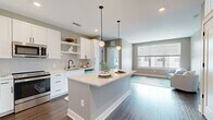 Located at 1055 Alpharetta St in Roswell, GA, this thoughtfully designed one-bedroom, one-bathroom residence offers a smart and efficient layout across a single floor. The open-concept kitchen is a standout feature, showcasing white shaker cabinetry, quartz countertops, stainless steel appliances, and a peninsula island with bar seating — all illuminated by pendant lighting and recessed fixtures. Rich hardwood-style flooring flows throughout the main living areas, adding warmth and continuity to the space.

The living room is bright and inviting, benefiting from large windows with outdoor views and direct access to a private balcony through a glass door, allowing abundant natural light to fill the room. The bedroom is carpeted and comfortably sized, featuring a ceiling fan, multiple windows, and a calm, neutral color palette that creates a relaxing retreat.

The walk-in closet provides well-organized shelving and hanging space on multiple levels. The bathroom is finished with elegant marble-look tile in the tub/shower surround, dark hardwood-style flooring, a white vanity with a undermount sink, and matte black fixtures that lend a contemporary touch. Neutral gray tones are carried throughout the home, creating a cohesive and modern aesthetic.