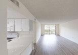 Located at 17350 NW 68 Ave in Miami Gardens, Florida, this single-floor residence offers a clean, contemporary aesthetic throughout. The open-concept layout connects the living area to the kitchen, creating a bright and airy atmosphere enhanced by floor-to-ceiling sliding glass doors that fill the space with natural light and provide outdoor views of lush greenery. Wood-look plank flooring runs throughout the main living areas and bedrooms, complementing the crisp white walls and textured ceilings.

The kitchen features a two-tone design with sleek, high-gloss white upper cabinetry and dark lower cabinets, paired with white quartz countertops and a pass-through breakfast bar. A full suite of appliances, including a range, built-in microwave, and dishwasher, is included. Recessed lighting adds a polished finish.

The bedrooms are generously sized, each with large windows offering views of palm trees and landscaping. The primary suite includes access to a spacious walk-in closet outfitted with wire shelving and hanging rods. The bathroom is well-appointed with a wide vanity featuring dark wood cabinetry, a white countertop, and a glass-enclosed walk-in shower with neutral tile detailing. A secondary full bathroom mirrors the same refined design, ensuring consistent style throughout this well-appointed home.