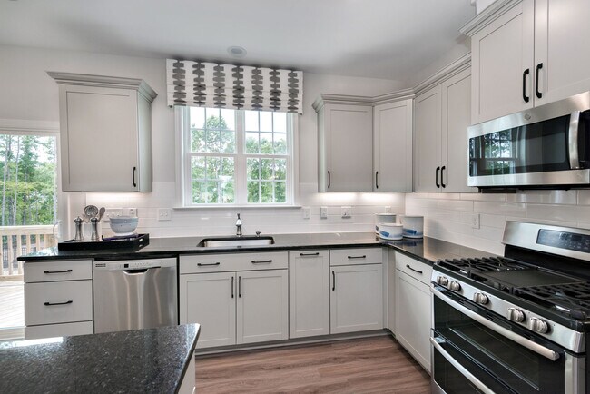 Cocinas inspiradas en chefs con electrodomésticos de acero inoxidable, encimeras de granito y salpicadero de azulejos. - Avalon Townhomes Brier Creek