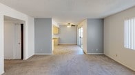 Located at 3030 W Acacia Ave in Hemet, California, this single-story unit offers a practical and well-organized floor plan suitable for everyday living. The open living and dining area is finished with neutral carpet flooring and accented by cool gray feature walls, creating a clean and welcoming atmosphere. A ceiling fan with a light fixture provides both comfort and illumination, while a sliding glass door opens to an outdoor area, allowing natural light to flow into the space. The kitchen is thoughtfully appointed with light wood cabinetry offering ample storage, a gas range, a full-size refrigerator, and tile flooring — all beneath a tray ceiling with track lighting that adds a touch of character. The bedrooms are carpeted and feature sliding closet doors and windows with vertical blinds, bringing in natural light and outdoor views. The bathrooms are clean and functional, each equipped with a tub and shower combination, chrome fixtures, and tile flooring. Throughout the unit, textured ceilings and neutral white walls provide a bright, move-in-ready canvas. The overall ambiance is understated and practical, with a layout that maximizes usability across every room.