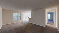 This single-floor residence offers a well-planned layout with a comfortable, functional flow throughout. The living and dining area is generously proportioned, featuring plush carpeting, neutral-toned walls, and large windows that bring in abundant natural light while offering views of surrounding greenery. A textured ceiling adds subtle character to the space, and the open sightlines toward the kitchen create a cohesive, connected atmosphere.

The kitchen is a standout feature, outfitted with white shaker-style cabinetry, marble-look countertops, a tile backsplash, and wood-look flooring. Black appliances, including a refrigerator, range, and dishwasher, provide a clean contrast against the bright cabinetry. A peninsula with additional counter space connects the kitchen to the living area, making it practical for both cooking and casual dining.

The bedrooms are carpeted and well-sized, each receiving natural light through windows with outdoor views. Closet storage is included, with at least one bedroom featuring a sliding-door closet. The bathrooms are finished with marble-look countertops, modern fixtures, and clean, neutral tones, with one bathroom including a soaking tub. Overall, the space presents a bright, refreshed interior with consistent finishes throughout.