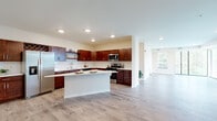 This single-floor residence offers a thoughtfully designed layout with modern finishes and functional living spaces throughout. The open-concept kitchen is a standout feature, showcasing rich dark wood cabinetry, white quartz countertops, a classic subway tile backsplash, and a full suite of stainless steel appliances including a refrigerator with ice maker, gas range, microwave, and dishwasher. A central island provides additional prep and dining space, while recessed lighting illuminates the area. Light wood-look flooring flows seamlessly through the main living areas, enhancing the bright, airy ambiance. The spacious living area connects to a private balcony through floor-to-ceiling sliding glass doors and large windows, inviting generous natural light and outdoor views. Bedrooms are carpeted for comfort and feature ceiling fans, ample closet space with built-in shelving, and walk-in storage options. The primary bathroom is elegantly appointed with a dark granite countertop, white cabinetry, a backlit vanity mirror, and decorative patterned tile flooring. A dedicated in-unit laundry room with side-by-side washer and dryer adds everyday convenience. Throughout the unit, clean neutral tones, white trim, and recessed lighting contribute to a polished, contemporary aesthetic.
