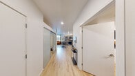 Located at 11201 Roosevelt Way NE in Seattle's Maple Leaf neighborhood, this thoughtfully designed single-floor unit makes efficient use of its compact footprint through an open-concept layout and modern finishes throughout. Light hardwood flooring runs continuously through the space, creating a cohesive and airy feel.

The combined kitchen and living area forms the heart of the unit. The kitchen is equipped with stainless steel appliances—including a range, microwave, and refrigerator—set against warm wood-toned cabinetry and a tile backsplash. A bar-height table with stools serves as both a dining and prep area. The living room features a patterned accent wall, large window with urban views, and recessed lighting that keeps the space bright and welcoming.

A dedicated office is accessible via a sliding barn door, offering a focused workspace with dark accent walls, room for a desk setup, and a comfortable seating area—providing a clear separation between work and living.

The bathroom is well-appointed with wood-finish cabinetry, a granite-topped vanity, a large mirror, and a stacked washer/dryer unit conveniently integrated into the space.

A separate walk-in closet provides organized storage with open hanging racks and overhead shelving, completing this efficiently planned modern residence.