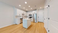 Located at 100 Windflower Ln in Daytona Beach, FL, this modern single-floor residence offers a thoughtfully designed layout with clean finishes and a bright, airy aesthetic throughout. Light hardwood flooring runs continuously across every room, tying the space together with a cohesive, contemporary feel.

The open-concept kitchen and living area forms the heart of the home. The kitchen is outfitted with crisp white cabinetry accented by matte black hardware, a marble-style tile backsplash, white quartz countertops, and a full suite of stainless steel appliances including a refrigerator, electric range, over-the-range microwave, and dishwasher. A central island provides additional prep space and casual seating. Recessed lighting illuminates the kitchen, while a ceiling fan serves the adjoining living area, which receives natural light through large windows fitted with horizontal blinds.

The generously sized bedroom is a serene retreat, featuring neutral tones, a ceiling fan, and windows that invite ample natural light. A dedicated closet provides convenient storage.

The bathroom is finished in a modern style with white cabinetry, a white quartz vanity, matte black fixtures and hardware, a large mirror, and a tiled tub-shower combination. The overall design throughout is clean, minimal, and move-in ready.