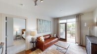 This single-floor residence offers a thoughtfully designed layout that seamlessly blends functionality with modern style. The open-concept living area is anchored by hardwood floors, track lighting, and large sliding glass doors that open to a private balcony, flooding the space with natural light and providing pleasant outdoor views of surrounding greenery. A comfortable living room flows directly into the kitchen, which features warm-toned wood cabinetry, granite countertops, a tile backsplash, a peninsula with a double sink, pendant lighting, and black appliances including a range, microwave, refrigerator, and dishwasher. The multiple bedrooms are carpeted for comfort, each offering generous windows with outdoor views, ceiling fans, and ample space for furnishings. The primary bedroom connects to a well-appointed bathroom featuring granite countertops, wood cabinetry, tile flooring, and access to a dedicated walk-in closet. A second bathroom mirrors this finish quality, also offering a walk-in closet. Throughout the residence, a neutral color palette, consistent warm wood accents, and tasteful design details create a cohesive and inviting atmosphere that is both practical and refined.