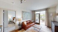 This single-floor residence offers a thoughtfully designed layout that seamlessly blends functionality with modern style. The open-concept living area is anchored by hardwood floors, track lighting, and large sliding glass doors that open to a private balcony, flooding the space with natural light and providing pleasant outdoor views of surrounding greenery. A comfortable living room flows directly into the kitchen, which features warm-toned wood cabinetry, granite countertops, a tile backsplash, a peninsula with a double sink, pendant lighting, and black appliances including a range, microwave, refrigerator, and dishwasher. The multiple bedrooms are carpeted for comfort, each offering generous windows with outdoor views, ceiling fans, and ample space for furnishings. The primary bedroom connects to a well-appointed bathroom featuring granite countertops, wood cabinetry, tile flooring, and access to a dedicated walk-in closet. A second bathroom mirrors this finish quality, also offering a walk-in closet. Throughout the residence, a neutral color palette, consistent warm wood accents, and tasteful design details create a cohesive and inviting atmosphere that is both practical and refined.
