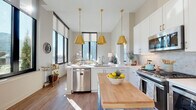 Located in the heart of Atlanta, GA, this thoughtfully designed single-floor residence offers a refined urban living experience. The open-concept kitchen is a standout, outfitted with crisp white shaker cabinetry, a mosaic tile backsplash, stainless steel appliances, and generous counter space. A butcher block island adds warmth and functionality, while a trio of gold pendant lights overhead lend an elegant, contemporary touch. Large windows flood the kitchen with natural light and frame sweeping city views.

The living room continues this bright, airy atmosphere with soaring ceilings and dramatic floor-to-ceiling windows that showcase the Atlanta skyline. Warm hardwood flooring runs throughout the main living areas, anchoring the sophisticated design.

The bedrooms are well-proportioned and serene, each benefiting from natural light and thoughtful layouts. The primary suite connects directly to an en-suite bathroom featuring a glass-enclosed walk-in shower, a double vanity with rich wood cabinetry, white quartz countertops, and a herringbone-patterned tile floor. A secondary bathroom echoes this refined aesthetic with similar tilework and clean finishes.

Practical conveniences include an in-unit laundry closet with a full-size washer and dryer, neatly tucked behind louvered doors. Throughout the residence, neutral tones, high ceilings, and quality finishes create a cohesive, polished atmosphere ideal for modern city living.