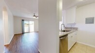 This well-appointed single-floor residence offers a clean, modern aesthetic throughout its thoughtfully designed layout. The open living area is anchored by warm hardwood-style flooring, a ceiling fan, and a sliding glass door that floods the space with natural light and provides direct access to a private outdoor patio. Wall-mounted accent lighting adds a welcoming ambiance to the living space.

The galley-style kitchen is efficiently designed with white shaker cabinetry, granite-look countertops, a stainless steel undermount sink, and a full suite of stainless steel appliances including a gas range, dishwasher, microwave, and refrigerator. Neutral tile flooring completes the kitchen's clean, functional look.

The bedrooms continue the hardwood-style flooring and feature ceiling fans, generous closet space, and sliding glass doors opening to the outdoor area, ensuring natural light and ventilation throughout. The space includes two bathrooms: a full bathroom with white cabinetry, granite countertops, and a shower/tub combination, and a secondary bathroom finished with tile flooring and a shower/tub unit. Both bathrooms maintain a consistent, crisp white palette. Overall, the residence presents a bright, move-in-ready environment with cohesive finishes and functional design.