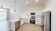 This 640 square foot apartment in Cedar Rapids, Iowa, offers a thoughtfully designed living space that maximizes functionality. The single-floor layout encompasses one bedroom, one bathroom, a modern kitchen, and a dedicated laundry area. The bedroom, measuring 130 square feet, provides ample space and features a large window that floods the room with natural light. The kitchen is a highlight, boasting white cabinetry, stainless steel appliances, and a convenient breakfast bar. Pendant lighting adds a touch of style while illuminating the cooking and dining areas. The bathroom is clean and efficient, with a vanity, toilet, and shower/tub combination. The in-unit laundry room is equipped with a stacked washer and dryer, along with built-in shelving for storage. Throughout the apartment, neutral tones and light wood-look flooring create a bright, airy atmosphere. The living areas feature plush carpeting for added comfort. With its clever use of space and modern amenities, this apartment offers an ideal living solution for singles or couples seeking a compact yet well-appointed home in an urban setting.