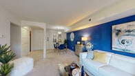 This single-floor residence at 3412 Willow Lake Dr in Kalamazoo, Michigan offers a thoughtfully arranged layout designed for comfortable everyday living. The living area serves as the centerpiece of the home, distinguished by a striking cobalt blue accent wall that adds a bold visual focal point. Plush carpeting runs throughout the space, and a sliding glass door floods the room with natural light while providing direct access to an outdoor patio area with views of surrounding greenery. The open layout connects the living area seamlessly to a dedicated dining space, defined by an elegant arched passageway.

The kitchen is equipped with warm oak cabinetry, ample counter space, a double sink, and includes a dishwasher and electric range, offering practical functionality. The primary bedroom is generously sized with soft carpeting, natural light from large windows, and convenient access to a walk-in closet. A second bedroom functions well as a guest room or home office, featuring its own sliding glass door to an outdoor area. The bathroom includes a wide vanity countertop with an oversized mirror. Overall, the home presents a clean, well-organized interior with a cohesive blue-and-white color palette throughout.