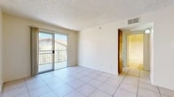 Located at 2736 W Lincoln Ave in Anaheim, CA, this single-floor, 2-bedroom, 2-bathroom residence offers a well-organized layout designed for comfortable everyday living. The open-concept living and dining area is bright and airy, featuring large-format white tile flooring and a sliding glass door that opens to a private balcony with views of the surrounding neighborhood. Textured ceilings and clean white walls run throughout, contributing to a light, neutral aesthetic. The kitchen is efficiently designed with warm wood cabinetry, granite-look countertops, a built-in electric range, and tile flooring, flowing seamlessly into a dedicated dining space appointed with a ceiling fan. The bedrooms offer a contrast in flooring, with the primary bedroom featuring light hardwood-style floors, a natural light source via a window, and a built-in closet with shelving. The hallway connects the living spaces to the two full bathrooms, one of which includes a wood-grain vanity with a stone-look countertop and tile flooring. A dedicated closet provides additional storage. The exterior presents a Mediterranean-influenced stucco facade with a tiled roof and lush greenery, set within a gated community in Anaheim.