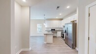 Located at 7011 Star Oaks Ln in Charlotte, NC, this thoughtfully designed one-bedroom, one-bathroom residence offers a comfortable and modern living experience on a single floor. The open-concept kitchen and living area serves as the heart of the home, featuring light hardwood-style flooring, recessed lighting, and pendant lights that create a warm, inviting ambiance. The kitchen is well-equipped with crisp white shaker cabinetry, granite countertops, a subway tile backsplash, a center island with a undermount sink, and a full suite of stainless steel appliances including a French door refrigerator, electric range, and dishwasher. The living area flows seamlessly toward a sliding glass door that opens onto a private balcony, filling the space with natural light. The bedroom is carpeted for comfort, features a ceiling fan, a large window with outdoor views, and includes a double-door closet. The bathroom is finished with granite countertops, a white vanity, hardwood-style flooring, and accessibility-friendly grab bars. Two closets provide ample storage throughout the residence, and a dedicated entrance completes this well-rounded, move-in-ready home.