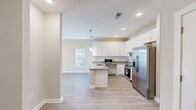 Located at 7011 Star Oaks Ln in Charlotte, NC, this thoughtfully designed one-bedroom, one-bathroom residence offers a comfortable and modern living experience on a single floor. The open-concept kitchen and living area serves as the heart of the home, featuring light hardwood-style flooring, recessed lighting, and pendant lights that create a warm, inviting ambiance. The kitchen is well-equipped with crisp white shaker cabinetry, granite countertops, a subway tile backsplash, a center island with a undermount sink, and a full suite of stainless steel appliances including a French door refrigerator, electric range, and dishwasher. The living area flows seamlessly toward a sliding glass door that opens onto a private balcony, filling the space with natural light. The bedroom is carpeted for comfort, features a ceiling fan, a large window with outdoor views, and includes a double-door closet. The bathroom is finished with granite countertops, a white vanity, hardwood-style flooring, and accessibility-friendly grab bars. Two closets provide ample storage throughout the residence, and a dedicated entrance completes this well-rounded, move-in-ready home.