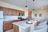 Located at 121 S Bristol St in Sun Prairie, Wisconsin, this well-appointed 2-bedroom, 3-bathroom residence offers a thoughtfully designed single-floor layout with a clean, contemporary aesthetic throughout. Light wood-style flooring runs through the main living areas, complementing the neutral palette that gives the space an open and airy feel.

The kitchen is a standout feature, showcasing warm wood cabinetry, white quartz countertops, a classic subway tile backsplash, and stainless steel appliances including a gas range and refrigerator. A central island provides additional workspace and casual dining. Large sliding glass doors off the kitchen open to a private balcony, inviting abundant natural light and outdoor views.

The open living room flows naturally from the kitchen, offering bright windows with scenic tree-lined views and ample room for comfortable furnishings. The primary bedroom is generously sized, featuring plush carpet, natural light from large windows, and a sliding-door closet with built-in shelving. The bathrooms are modern and refined, with one featuring a backlit vanity mirror, dark quartz countertops, and a walk-in shower with glass enclosure, and another offering a full tub and shower combo. A dedicated laundry area with a full-size washer completes this well-rounded home.
