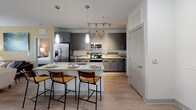 Located at 100 District Dr in Asheville, NC, this single-floor residence offers a thoughtfully designed layout with a seamless blend of modern finishes and comfortable living spaces. The open-concept kitchen is a standout feature, showcasing grey cabinetry, granite countertops, stainless steel appliances, a subway tile backsplash, and a central island with bar seating — ideal for both cooking and casual dining. Warm wood-look flooring runs throughout the kitchen and common areas, while pendant and track lighting add a polished touch. The living room is bright and inviting, bathed in natural light from large windows with blinds and drape treatments, and is anchored by a ceiling fan for year-round comfort. Multiple bedrooms are carpeted and generously sized, each featuring ceiling fans, natural light from well-positioned windows, and ample room for furnishings. The primary suite connects directly to a spacious walk-in closet with built-in wire shelving, which flows into the en suite bathroom. The bathroom is finished with grey cabinetry, granite countertops, a large mirror, and a glass-enclosed walk-in shower with tile surround and wood-look flooring. The overall ambiance is clean, neutral, and move-in ready.