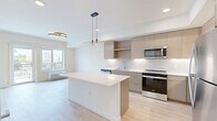 Located in Lynnwood, Washington, this thoughtfully designed one-bedroom, one-bathroom residence offers a clean, modern aesthetic throughout its single floor of living space. Light wood-tone flooring flows continuously through every room, creating a cohesive and airy atmosphere.

The kitchen is a standout feature, showcasing a contemporary two-tone cabinet design with warm wood uppers and sleek grey lowers, all complemented by white quartz countertops and a full suite of stainless steel appliances including a refrigerator, range, and over-the-range microwave. A central island with pendant lighting above provides additional prep space and a natural gathering point, while under-cabinet lighting adds both functionality and ambiance.

The bedroom is a comfortable retreat, featuring a large sliding-panel closet and a window that frames views of the surrounding Lynnwood neighborhood, allowing natural light to fill the room. Clean white walls keep the space feeling open and versatile.

The bathroom maintains the same modern sensibility, with warm wood cabinetry, light flooring, and crisp white walls. The layout is efficient and well-organized, making practical use of every inch. Overall, this residence offers a polished, move-in-ready environment with consistent modern finishes throughout.