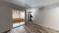 This single-floor unit offers a well-organized layout that maximizes functionality across its living spaces. The open-plan living and dining area is finished with durable, multi-toned wood-look flooring that extends throughout the entire unit, creating a cohesive and contemporary feel. A large sliding glass door floods the living area with natural light and provides direct access to a private balcony enclosed by a warm wooden privacy fence, offering a comfortable outdoor retreat.

The kitchen is efficiently designed with crisp white cabinetry, neutral stone-tone countertops, and a full suite of stainless steel appliances, including a refrigerator, electric range, and dishwasher. A stainless steel sink with a classic faucet rounds out the practical workspace.

The bedroom is a quiet, well-proportioned room featuring a ceiling fan, a sliding-door closet with built-in rod and shelving, and window blinds for natural light control. Neutral gray walls throughout the unit contribute to a clean, move-in-ready aesthetic.

The bathroom is neatly appointed with a white vanity paired with matching countertop, a tub-shower combination, and the same wood-look flooring found throughout the space. The overall ambiance of the unit is light, clean, and practical, making it a straightforward and comfortable living environment.