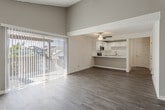 Located at 12592 W Chapman Ave in Garden Grove, California, this single-story residence offers a thoughtfully designed layout with a blend of modern updates and comfortable finishes throughout. The living area serves as the heart of the home, distinguished by soaring vaulted ceilings with exposed white beams and wood paneling, creating an airy, open atmosphere. Rich hardwood-style flooring flows through the main living spaces, while large sliding glass doors with vertical blinds provide direct access to an outdoor patio and fill the room with natural light.

The kitchen is well-appointed with crisp white shaker cabinetry, stone-look quartz countertops, a subway tile backsplash, and a full suite of stainless steel appliances including a range, over-the-range microwave, and dishwasher. A peninsula counter connects the kitchen to the living area, making the space ideal for everyday use.

The bedrooms feature plush carpeting, ceiling fans, and vertical blinds that allow adjustable natural light. One bathroom includes a vanity with quartz countertops, a tub-shower combination, and wood-style flooring. A second vanity area features built-in cabinetry and direct access to a dedicated walk-in closet, adding practical storage to the space.