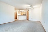 This single-floor, 2-bedroom, 1-bathroom unit offers a practical and comfortable layout across a well-utilized footprint. The combined kitchen and living area forms the heart of the space, with the kitchen featuring warm oak cabinetry, a peninsula with a built-in sink and dishwasher, a stainless steel microwave, an electric range, and a white refrigerator. Light tile flooring anchors the kitchen area, while plush carpet extends throughout the living space and bedrooms. Track lighting in the kitchen and living area provides ample illumination.

The spacious living room is a standout feature, highlighted by a ceiling fan and a set of French doors that flood the room with natural light and provide direct access to an outdoor area with green space views. A wall-mounted HVAC unit ensures year-round comfort.

The primary bedroom offers generous proportions with a large sliding-door closet and carpeted flooring. The second bedroom is similarly appointed with carpet and a closet, making it well-suited as a guest room or home office. A dedicated closet provides additional storage within the unit.

The bathroom features a wood-toned vanity with a wide countertop, a large mirror with overhead lighting, tile flooring, and a soaking tub. Warm oak wood trim and doors are consistent throughout, lending a cohesive and classic aesthetic to the entire space.