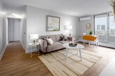 Located at 100 Forest Ave in Hamilton, Ontario, this well-appointed 2-bedroom, 1-bathroom unit offers a clean, modern aesthetic throughout. Light wood-look flooring flows seamlessly across the entire space, complemented by neutral wall tones that create a bright and cohesive atmosphere.

The open-concept kitchen and living area serves as the heart of the unit. The kitchen features white cabinetry, stainless steel appliances including a refrigerator, stove, and microwave, as well as a white quartz peninsula with a built-in sink and bar seating — ideal for casual dining. A tall pantry cabinet provides generous storage. The living area benefits from a large sliding glass door that floods the space with natural light and opens to sweeping views of the Hamilton skyline.

The primary bedroom is a comfortable, well-sized retreat with a wall-mounted air conditioning unit and a large window offering city views. The second bedroom is equally bright and tranquil, featuring its own window and ample floor space.

The full bathroom is finished with a white quartz vanity, white cabinetry with brushed nickel hardware, a tiled tub-shower combination, and wood-look flooring, maintaining the clean design language of the rest of the unit. A hallway connects all rooms efficiently, completing this thoughtfully designed urban residence.