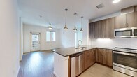 Located at 3765 Canfield St in Boulder, Colorado, this well-appointed 2-bedroom, 2-bathroom single-floor residence offers a thoughtfully designed layout with modern finishes throughout. The open-concept kitchen is a standout feature, showcasing rich wood-toned cabinetry that extends to the ceiling, a striking central island with a dark quartz countertop and gold-accented faucet, subway tile backsplash, and a full suite of stainless steel appliances including a French door refrigerator, range, microwave, and dishwasher. Pendant lighting above the island adds a warm, contemporary touch. The kitchen flows seamlessly into the living area, which features light wood-look flooring and a ceiling fan, with a door providing access to the outdoors. The primary bedroom is a comfortable retreat with plush carpeting, a ceiling fan, and a walk-in closet with dual hanging rods. The bathrooms are finished with warm wood vanities, quartz countertops, and a glass-enclosed tile shower. A dedicated in-unit laundry closet houses a full-size side-by-side washer and dryer. Recessed lighting and clean white walls create a bright, cohesive ambiance throughout, making this Boulder residence both functional and stylish.