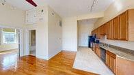 Located at 401 Brady St in downtown Davenport, Iowa, this one-bedroom, one-bathroom unit offers a well-designed single-floor layout. The open living area is anchored by warm hardwood flooring and impressively tall ceilings that lend a sense of spaciousness well beyond its footprint. A ceiling fan adds both comfort and character to the main living space, which is bathed in natural light from large windows overlooking the surrounding streetscape.

The galley-style kitchen is a standout feature, offering an extended run of warm wood cabinetry, granite-style countertops, and a full suite of appliances including a stainless electric range, microwave, dishwasher, and refrigerator. A peninsula counter provides a convenient casual dining or prep area, and tile flooring throughout the kitchen area offers easy maintenance.

The bedroom is comfortably sized, with hardwood floors, two windows with city views, and a ceiling fan. The full bathroom is finished with neutral tile in the tub/shower surround and on the floor, complemented by a wood vanity with a granite-style countertop. Track lighting in the kitchen and clean, neutral wall tones throughout give the space a cohesive, functional aesthetic.