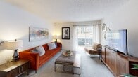 This 2-bedroom, 1-bathroom single-floor unit offers a practical and well-organized layout across a compact but efficiently designed footprint. The living room features soft carpet flooring, a textured ceiling, and a large sliding glass door that opens to a balcony, filling the space with natural light. Adjacent to the living area is a defined dining nook with carpet flooring, recessed lighting, and clean white walls that create a welcoming atmosphere for meals. The galley-style kitchen is lined with warm wood cabinetry, granite-toned countertops, and hardwood flooring, providing ample storage and counter workspace with white appliances throughout. The primary bedroom is generously sized, featuring plush carpet, a textured ceiling, and a wide sliding glass door that allows for abundant natural light and outdoor access. The second bedroom is comfortably scaled with carpet flooring, a window with natural light, and a textured ceiling. The shared full bathroom includes hardwood flooring, a granite-topped vanity with wood cabinetry, a full tub-shower combination with white tile surround, and a decorative curtain. Together, these spaces form a cohesive, functional home with consistent finishes throughout.