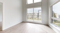 Located at 520 1st St E in North Vancouver, BC, this thoughtfully designed two-bedroom, two-bathroom residence offers a clean, modern aesthetic throughout. The open-concept layout connects the kitchen and living area seamlessly, with light wood-look flooring and crisp white walls creating a bright, airy atmosphere. The kitchen features white cabinetry, a subway tile backsplash, stainless steel appliances including a refrigerator, range, and built-in microwave, along with a central island with a sink. Large windows and a sliding glass door in the living area flood the space with natural light and provide direct access to a private balcony. Both bedrooms are well-proportioned with large windows; the primary bedroom includes a dedicated walk-in closet with built-in wire shelving. Additional closet storage is provided throughout the unit. The two bathrooms are finished in neutral tones, with one featuring a frameless glass sliding shower enclosure and stone-topped vanity. An in-unit laundry area houses a stacked washer and dryer. The hallway connects all rooms efficiently, contributing to a practical and well-organized floor plan suited for comfortable everyday living.